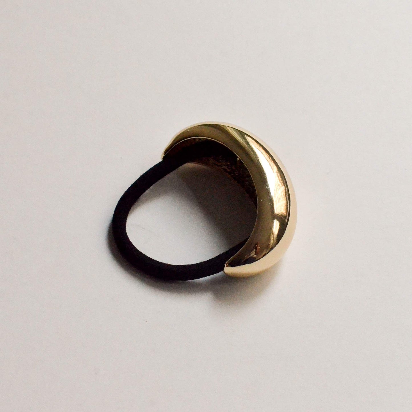 A wide crescent-shaped gold hair tie