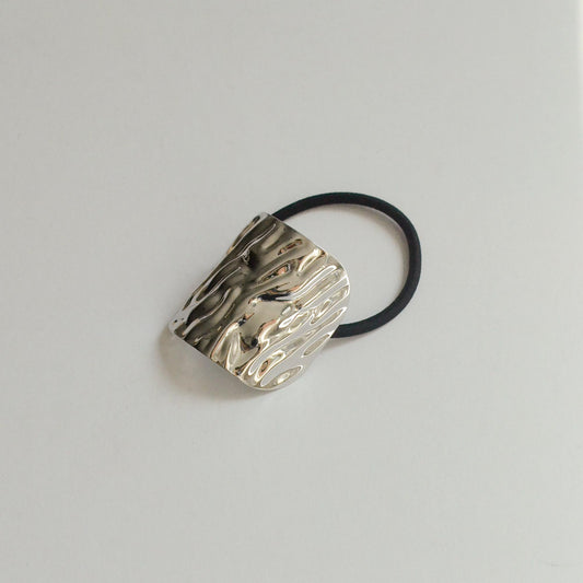 An elastic ponytail hair tie with a metal texture
