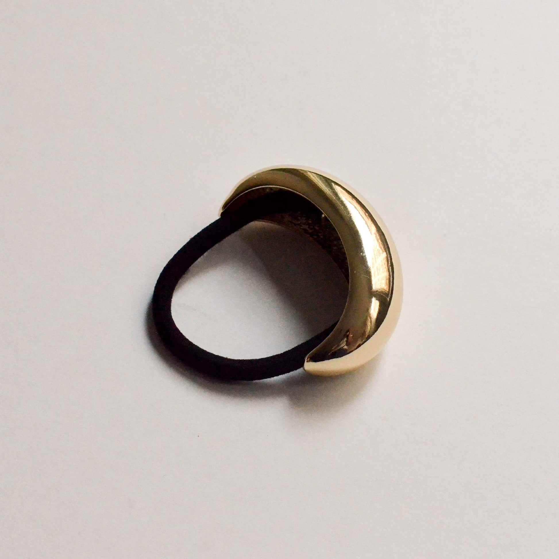 A wide crescent-shaped gold hair tie